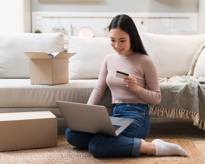 Person comfortably shopping online at home—holding a credit card