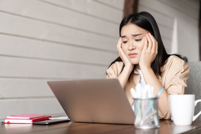 Young lady sitting at a desk, looking stressed while reviewing their credit card statement